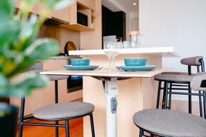 Une cuisine moderne dotée d’un îlot central, de tabourets de bar et d’un plan de travail blanc.
