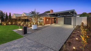 Ein modernes Haus mit überdachter Terrasse, einem gepflegten Rasen und dekorativer Beleuchtung.