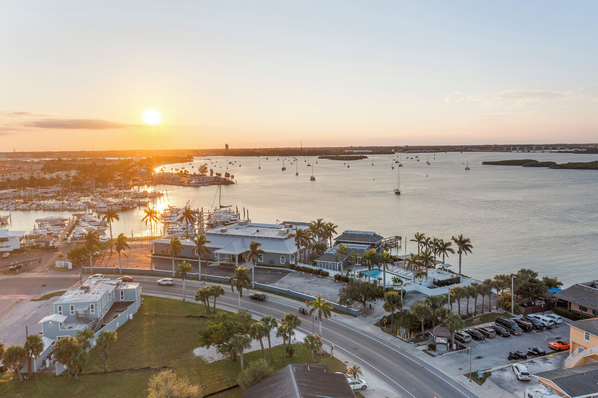 A marina with boats, a parking area, and buildings with a view of the water.