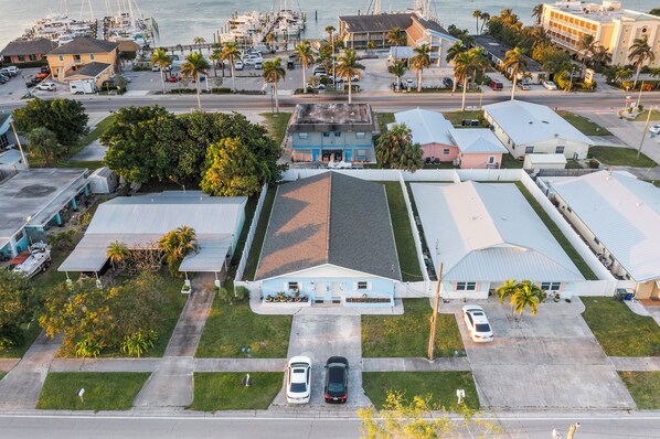 Zona residencial con una casa que tiene un garaje amplio, un camino de entrada con dos coches y un puerto deportivo al fondo.