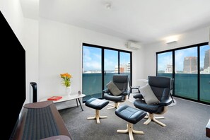 A modern lounge area with a view of the city skyline through large windows. - Panoramic View CBD 1 Bed Apt +OFFICE  (Collins) (Melbourne)
