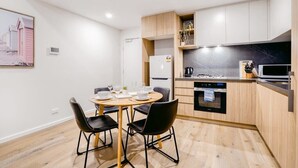 A modern kitchen with a dining area, wooden cabinets, a built-in oven, and a black countertop.