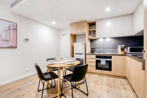 Eine moderne Küche mit Essbereich, Holzschränken, einem Einbauofen und einer schwarzen Arbeitsplatte.