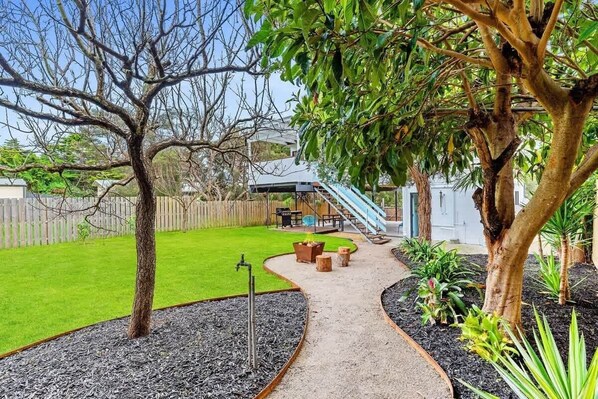 A backyard with a grassy lawn, a curved pathway, and a wooden deck.