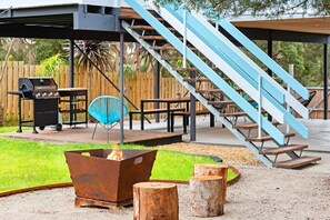 Un espacio al aire libre cubierto con una parrilla, un brasero y una escalera con barandillas azules.