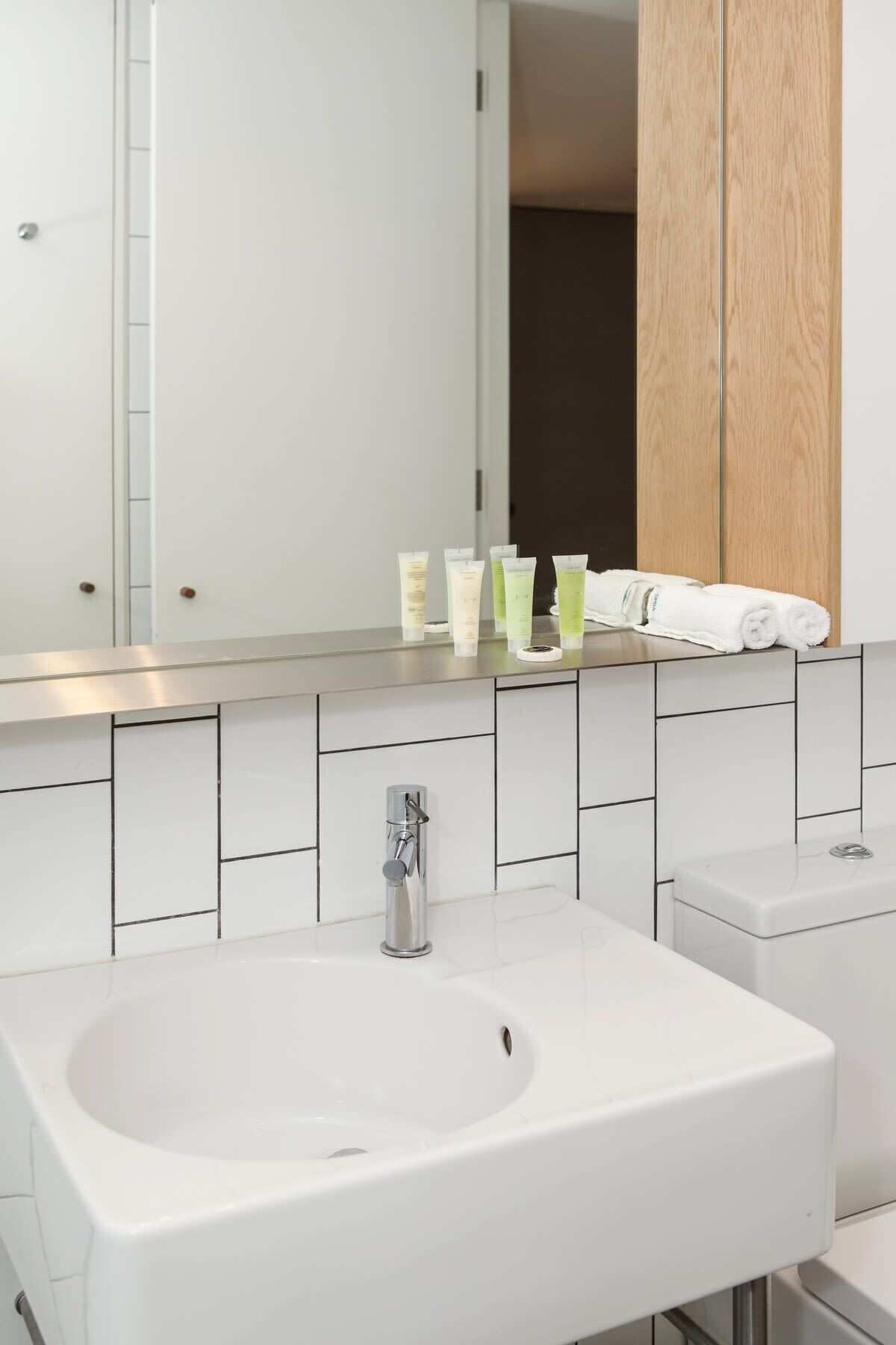 Une salle de bain moderne avec un grand lavabo, un miroir et des articles de toilette disposés sur le comptoir.
