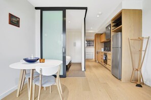 Een moderne keuken met een grote koelkast, houten kasten en een eethoek met een witte tafel en stoelen.