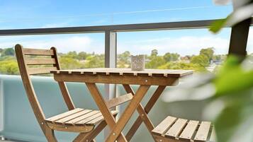 A wooden deck with a table and chairs, overlooking a green landscape.