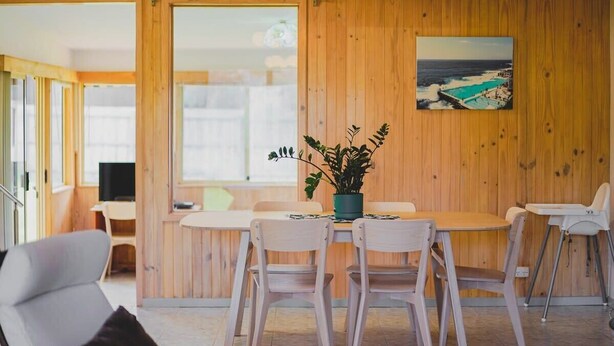A wooden-paneled room with a dining table and chairs, a potted plant, and a beach scene painting on the wall. - Rockpool House Short stroll to  St. Andrews Beach (Saint Andrews Beach)