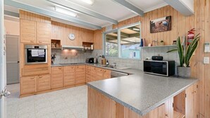 A modern kitchen with wooden cabinets, a built-in oven, a microwave, and a large window. - Rockpool House Short stroll to  St. Andrews Beach (Saint Andrews Beach)