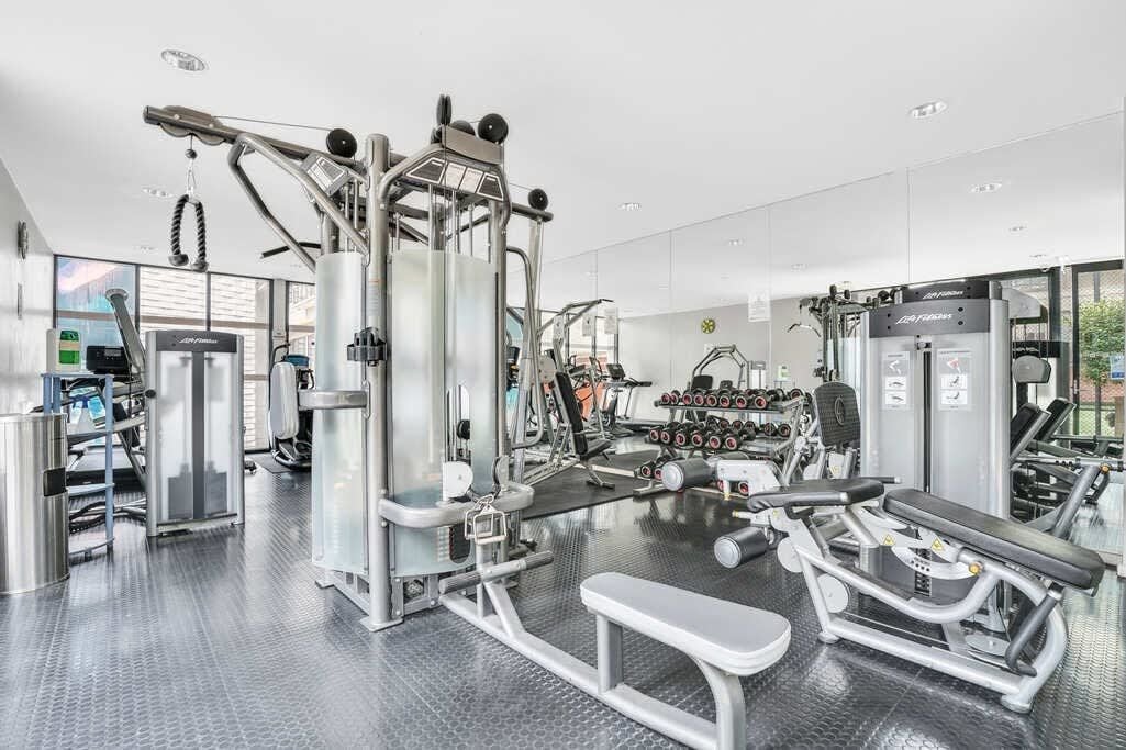 A modern gym with various exercise equipment, including a bench press, dumbbells, and weight machines.