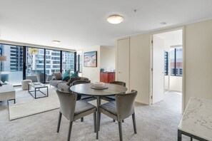 A modern living room with a round dining table, grey chairs, a sofa, and a coffee table. - Spacious&Cozy 2 bedroom City Point Melbourne Apt (Melbourne)