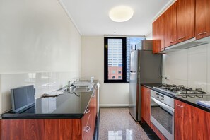 A modern kitchen with a black countertop, stainless steel appliances, and wooden cabinets. - Spacious&Cozy 2 bedroom City Point Melbourne Apt (Melbourne)
