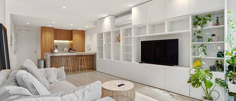 A modern living room with a sofa, a coffee table, and a TV wall unit.