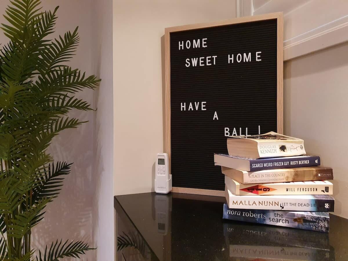 A home decor setup with a message board, a stack of books, and a plant.