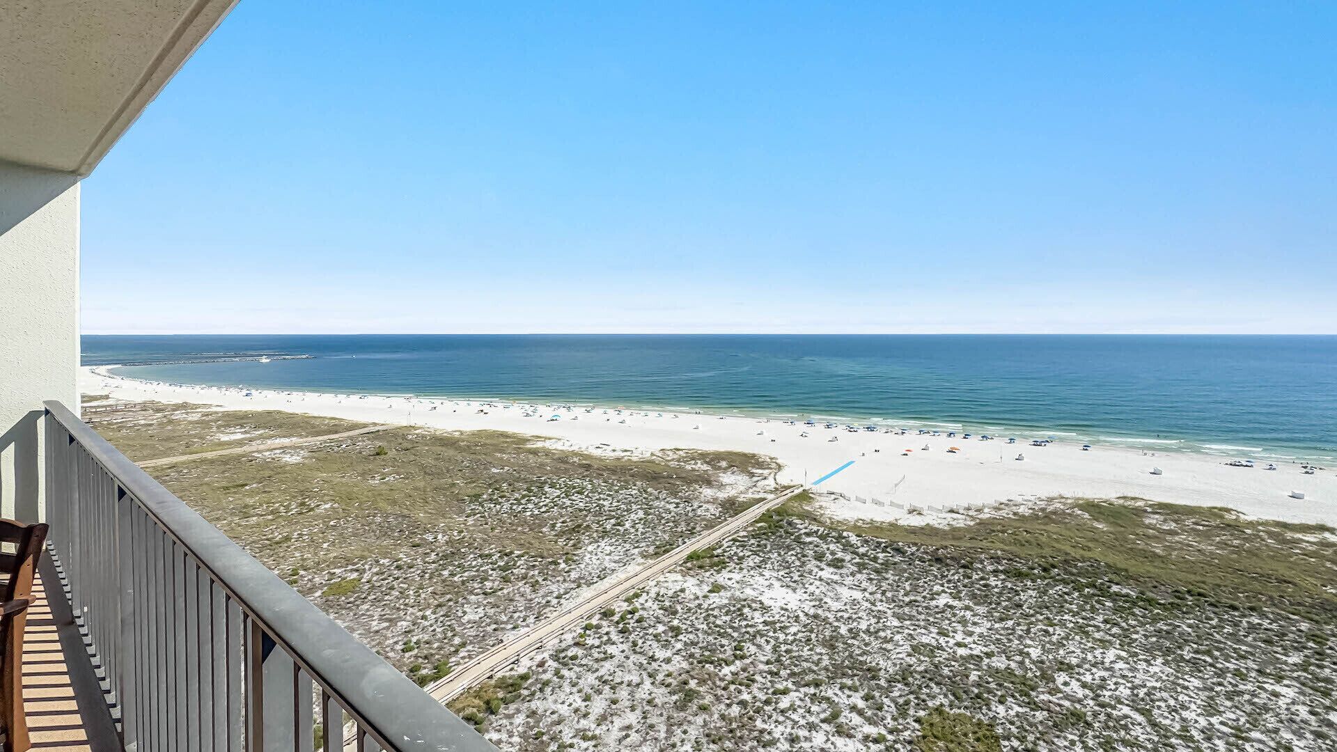 Uitzicht op een strand vanaf een balkon, met een heldere lucht.