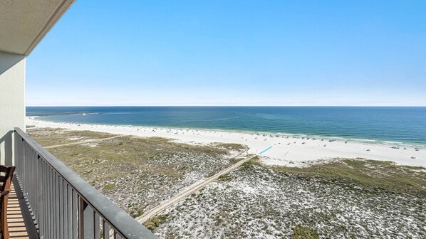 A beach view from a balcony with a clear sky.