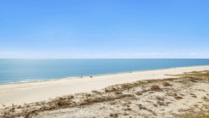 A wide beach with a clear sky, sandy shore, and a wooden fence in the foreground. - 1BR Beachfront Beauty! (Orange Beach)