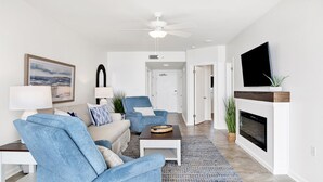 A modern living room with a sofa, armchairs, a coffee table, a fireplace, and a television. - 1BR Beachfront Beauty! (Orange Beach)
