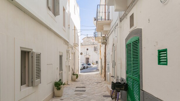 A narrow cobblestone street flanked by buildings with shutters and a bicycle parked on the right. - Residenza Vico Recupero by Wonderful Italy (Polignano a Mare)