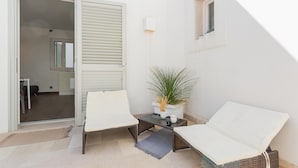 A small, open-plan living area with a sofa, a table with a plant, and a sliding door leading to a bathroom. - Residenza Vico Recupero by Wonderful Italy (Polignano a Mare)
