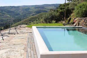 A rectangular pool with a stone border, surrounded by a stone patio and a few lounge chairs. - No Coração do Douro, Entre o Pinhão e Favaios, um Espaço de paz e Serenidade (Favaios)