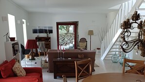 Un salon spacieux avec un canapé rouge, une table à manger en bois et un escalier menant à l’étage supérieur.