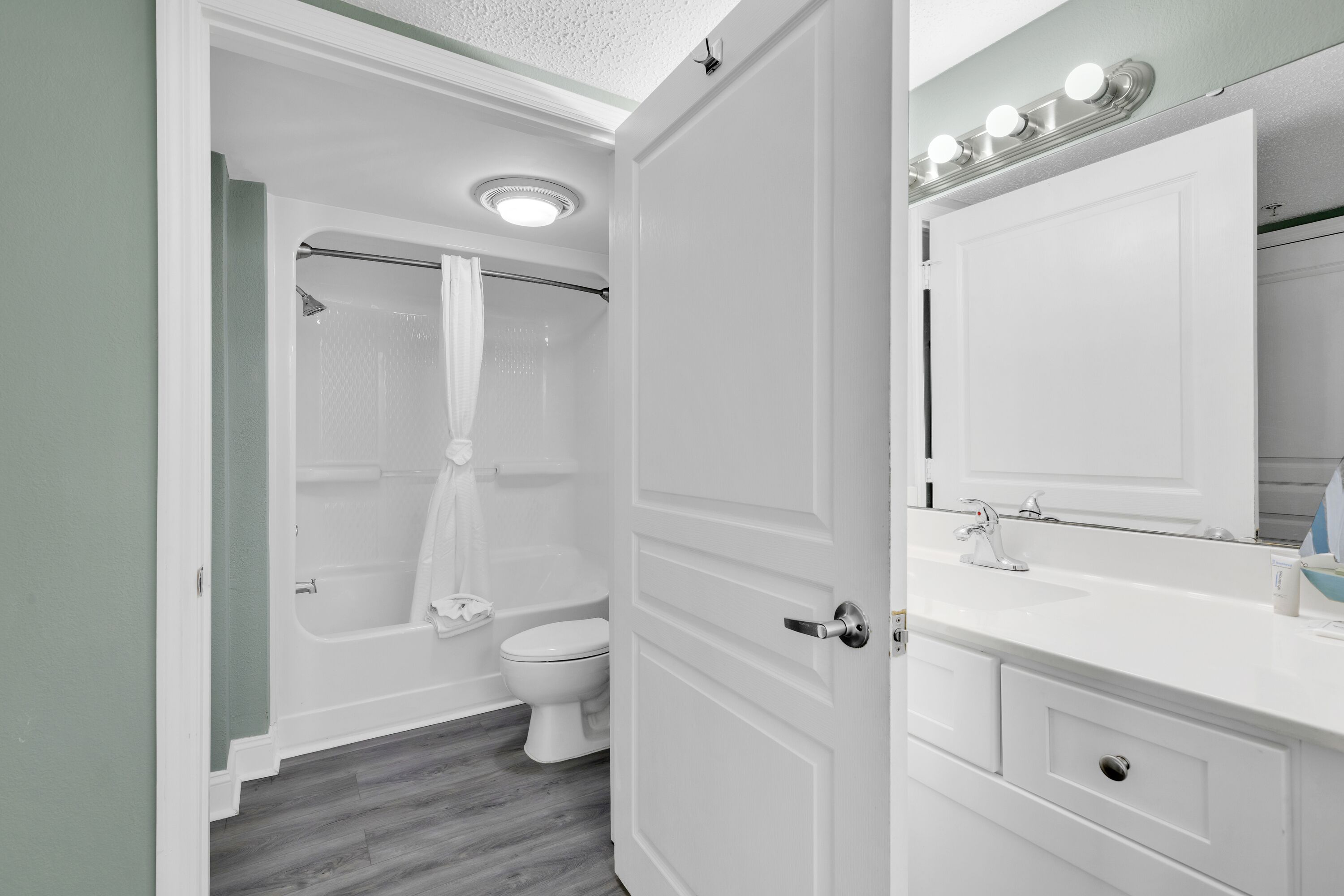 A bathroom with a shower, toilet, vanity with a mirror, and a sink.