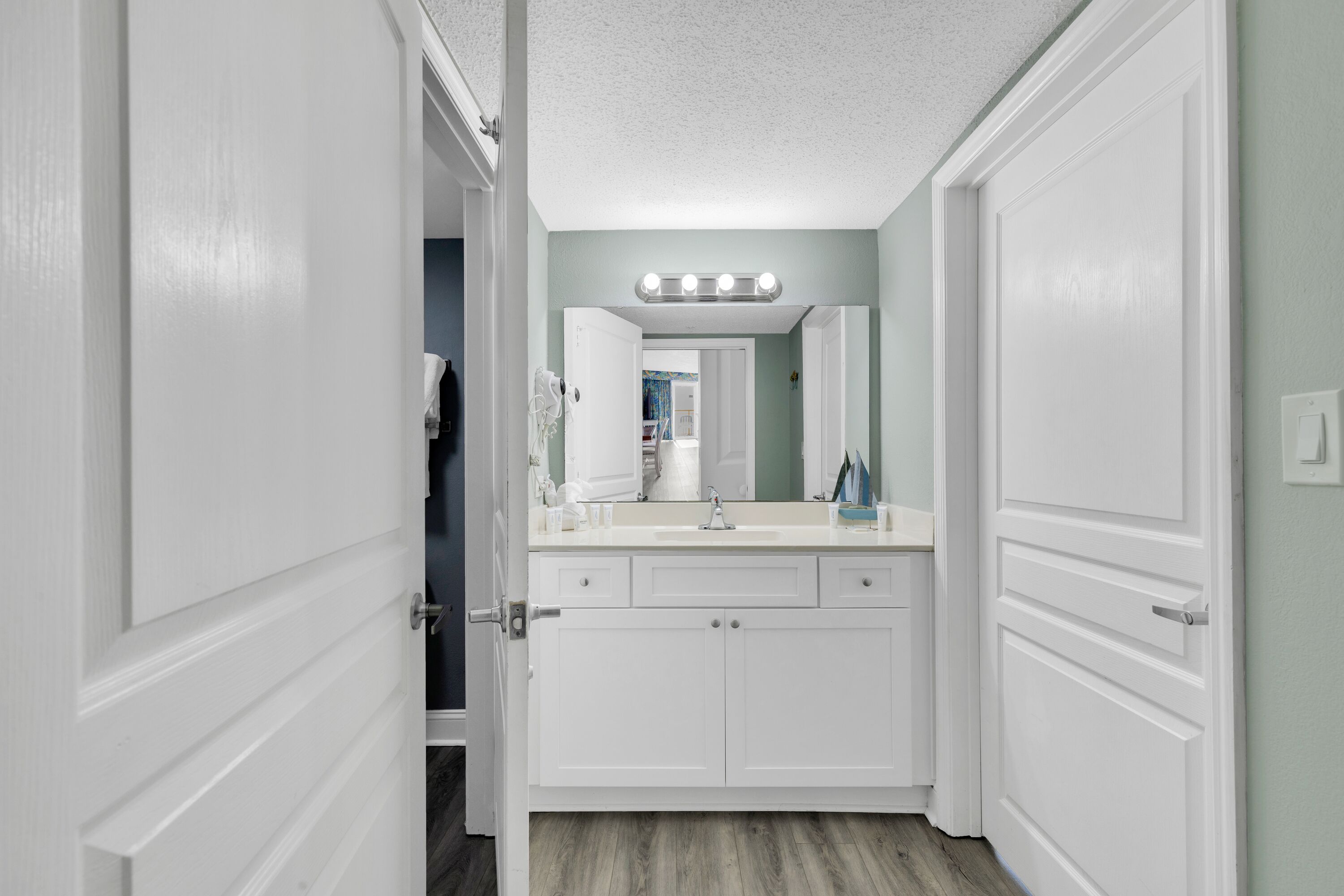 A bathroom with white cabinetry, a vanity with a mirror, and a light fixture above the mirror.