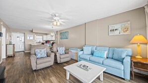 A living room with a light blue sofa, two beige armchairs, a white coffee table, and a ceiling fan. - Gulf-front retreat with 3 pools, patio, and beach access! (Orange Beach)