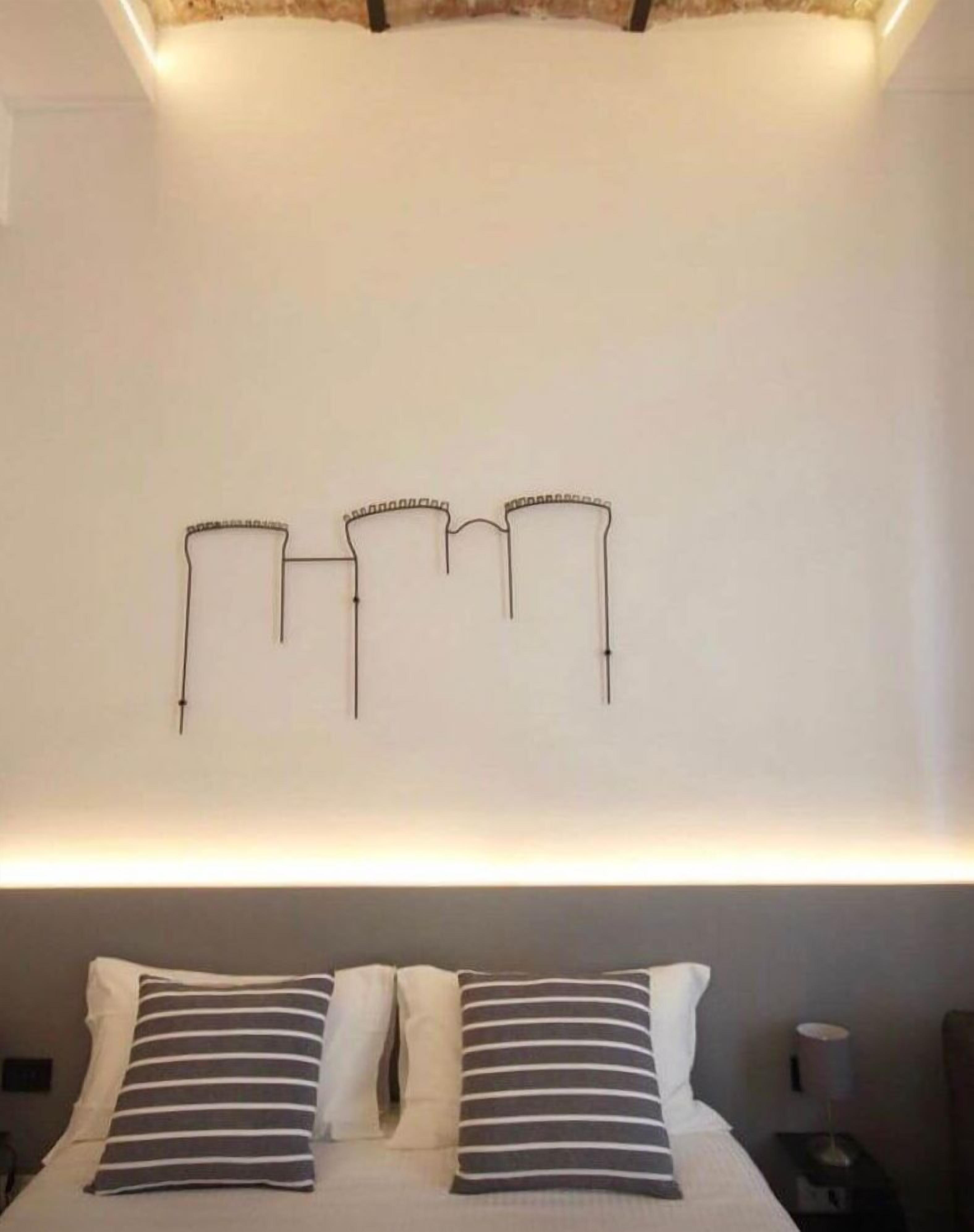 Ein Schlafzimmer mit einem Bett, zwei Kissen, einem Nachttisch und einer Wandleuchte.