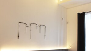 A modern interior with a white wall, a ceiling with exposed brick, and three black wall-mounted light fixtures. - VESUCHARME Suite Luxury Room (Naples)