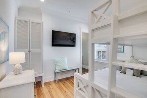 A modern bedroom with a bunk bed, a bedside table with a lamp, a bench, and a wall-mounted TV. - BVR 05 - Blue Heaven by Liquid Life (Orange Beach)