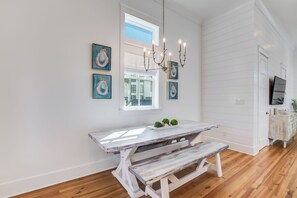 Ein Essbereich mit rustikalem Holztisch und Bank, einer Kandelaber und gerahmten Kunstwerken an der Wand.