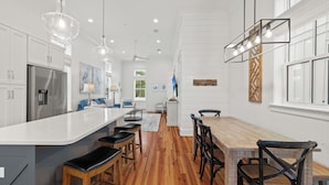 Une cuisine moderne dotée d’un îlot central, de planchers en bois et de luminaires suspendus.