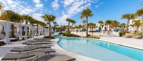 A pool area with lounge chairs, palm trees, and a clear sky.