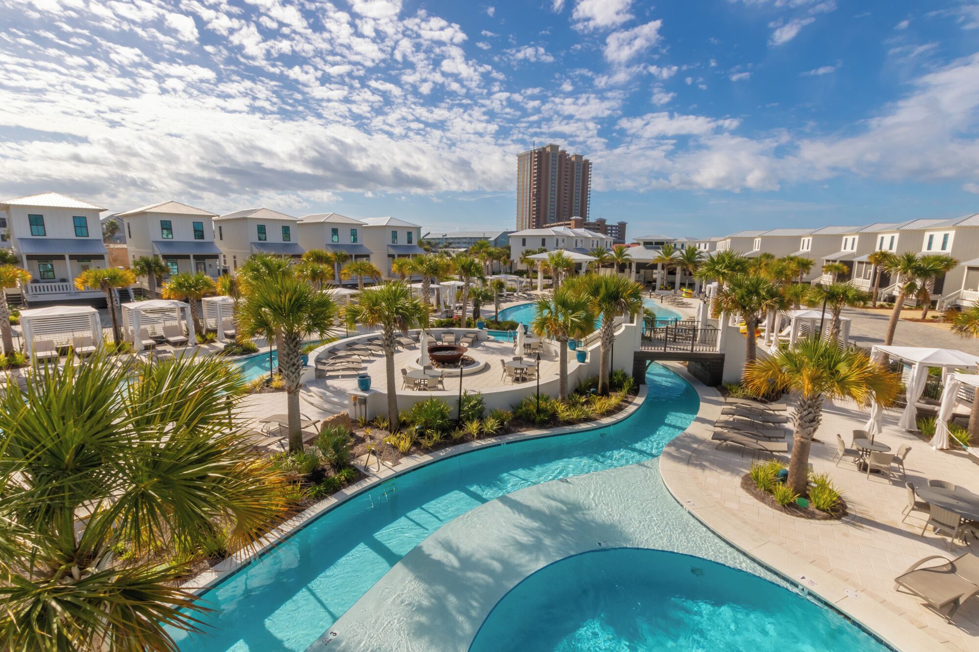 Un resort con una gran piscina, palmeras y varios edificios.