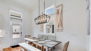 A dining area with a wooden table, benches, and a hanging light fixture. - BVR 40 - Isle Be Back by Liquid Life (Orange Beach)