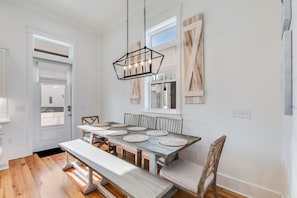 A dining area with a wooden table, benches, and a hanging light fixture.
