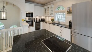 A modern kitchen with white cabinetry, a black granite countertop, and stainless steel appliances.