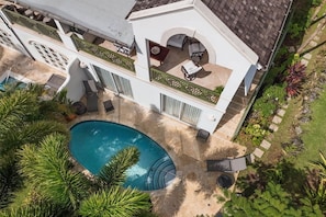Une maison à deux étages avec une piscine, un espace salon extérieur et un jardin.