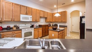 Una cocina moderna con armarios de madera, electrodomésticos de acero inoxidable y una isla central con un lavamanos.