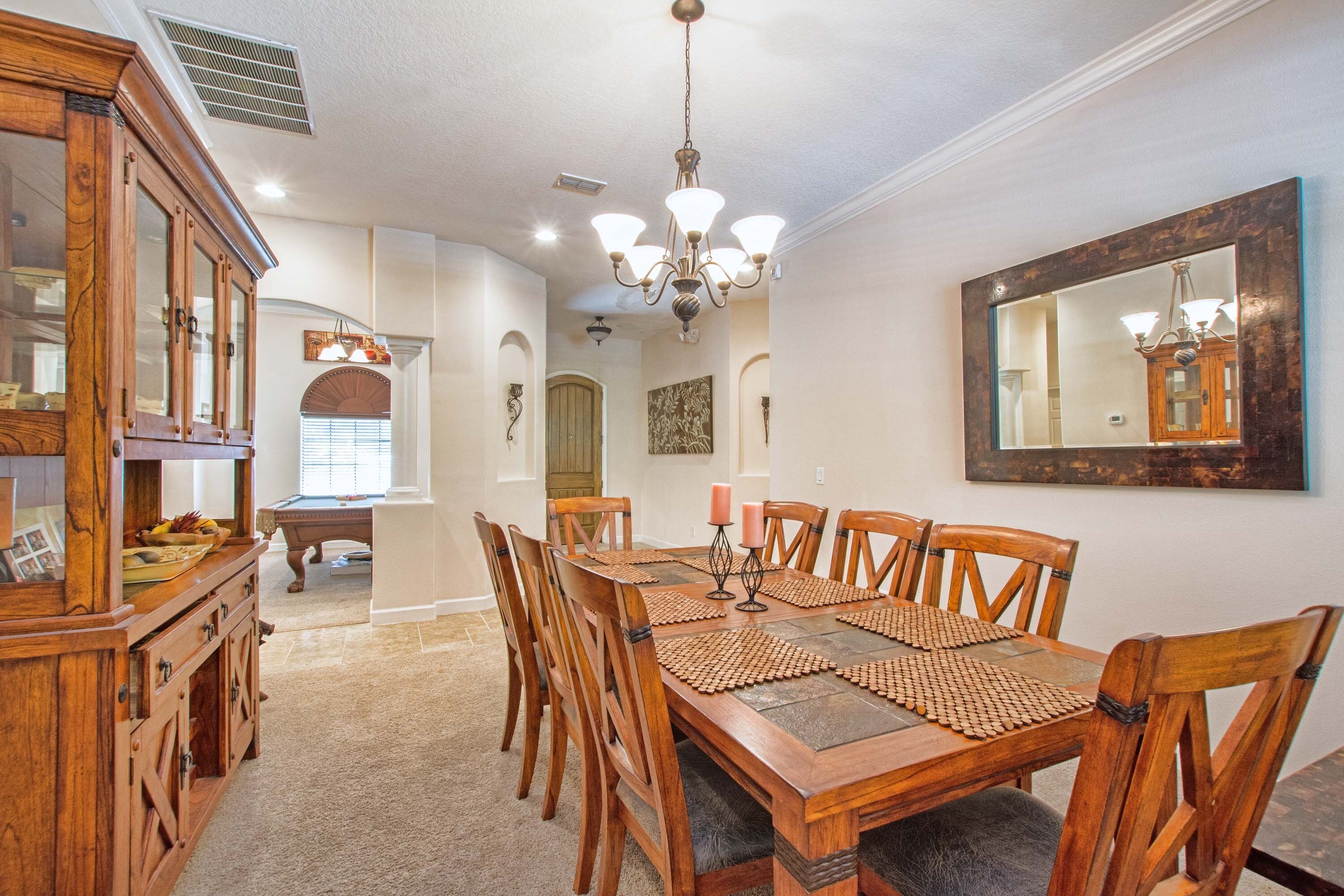 A dining room with a wooden table, chairs, and a chandelier.