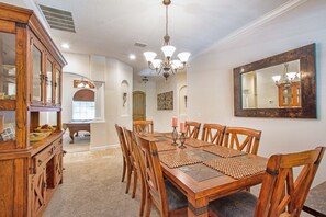 Comedor con mesa de madera, sillas y una araña.