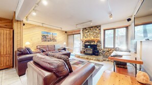 A cozy living room with a stone fireplace, leather sofas, and a wooden wall.