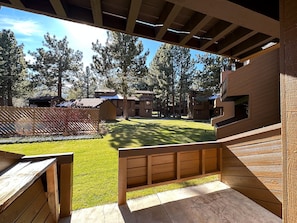 An outdoor seating area with wooden benches and a grassy lawn, surrounded by buildings with a modern architectural style.
