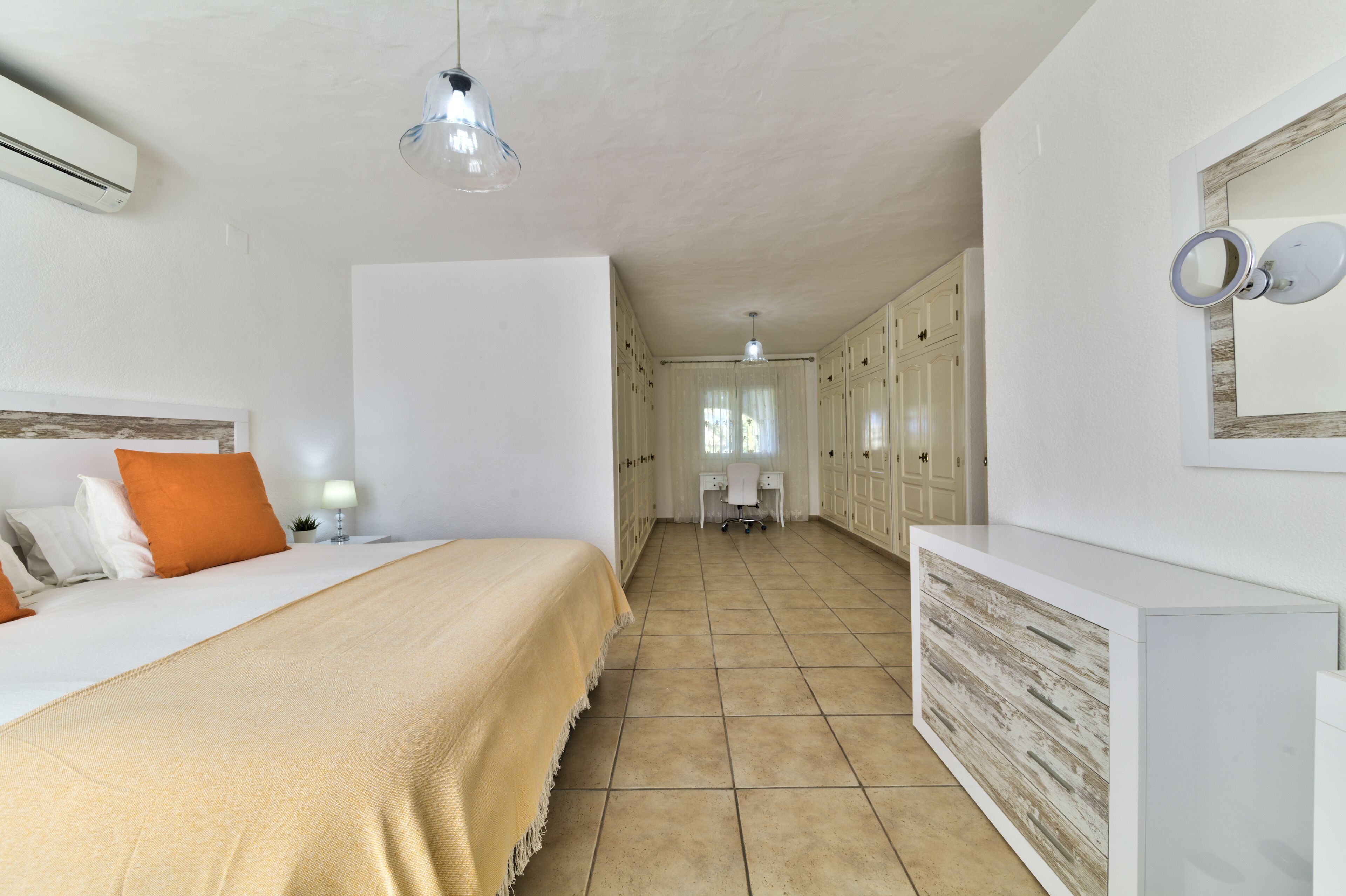 A bedroom with a bed, a bedside table, a desk, and a wardrobe.