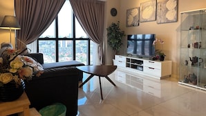 A modern living room with a sofa, TV, and city view through large windows. - Premium Retreat Suite Icon City (Petaling Jaya)