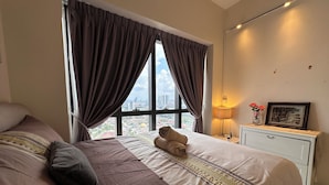 A bedroom with a large bed, a nightstand with a lamp, a framed picture, and a window with curtains. - Premium Retreat Suite Icon City (Petaling Jaya)