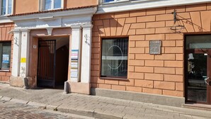 A building with a brick facade, a gated entrance, and a window with a circular design. - TyzenXL Luxury Vilnius Apartment (Vilnius)